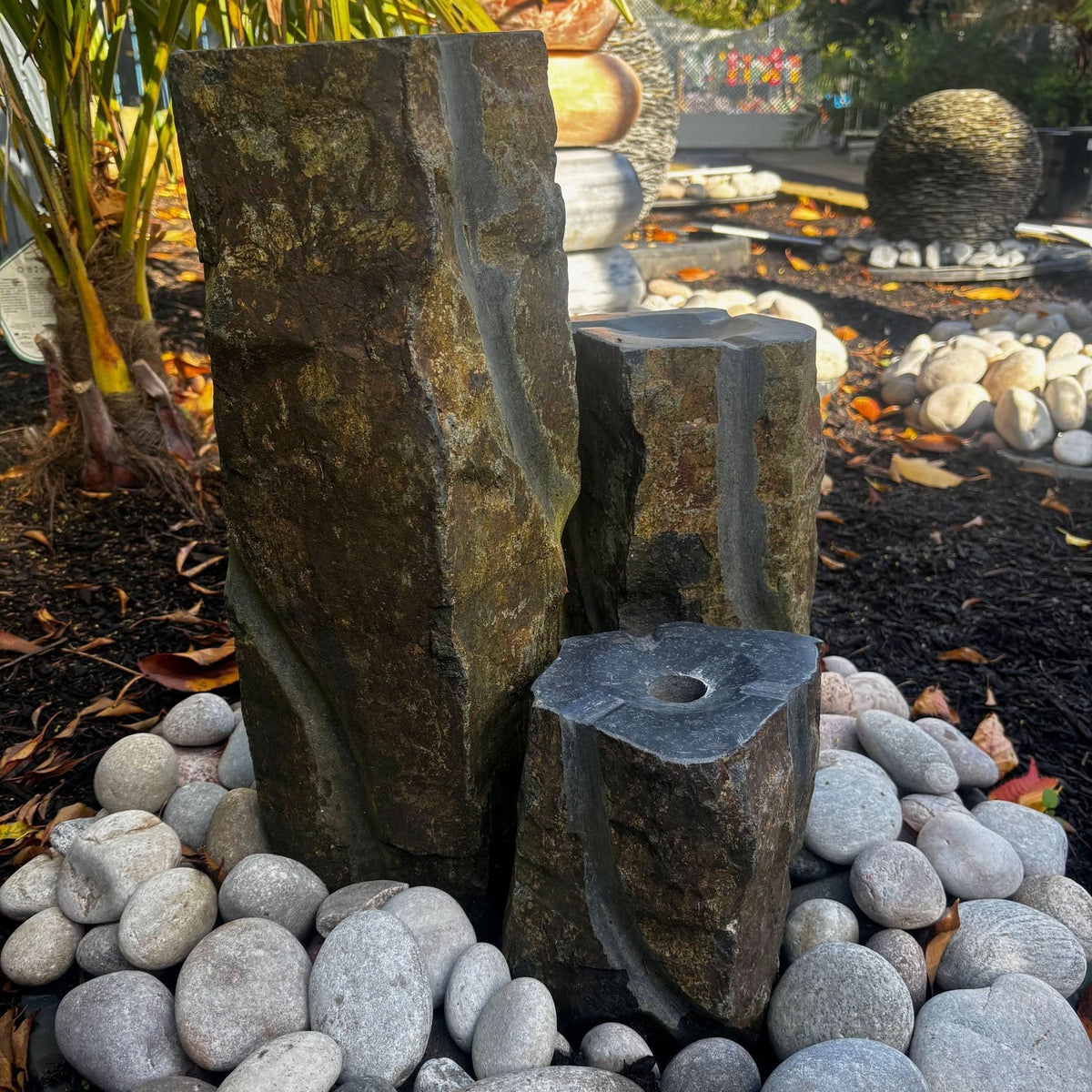 Mid Ulster Garden Centre hand carved basalt trio water feature with three natural stone columns in a garden setting