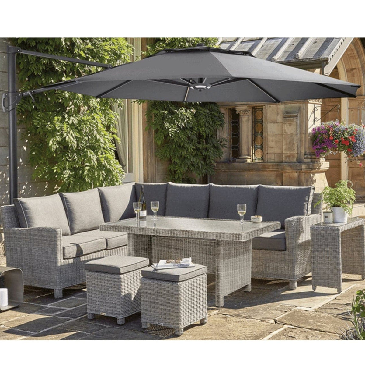 A 3.3m free arm parasol with LED lights and a Bluetooth speaker, displayed over an outdoor furniture set, set in a garden environment.